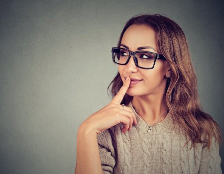 Woman in a questioning pose on a grey background