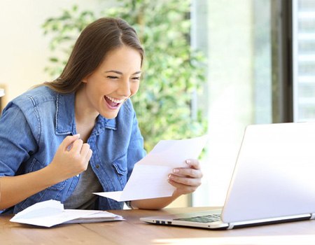 Woman at her desk excited that she can afford dental care